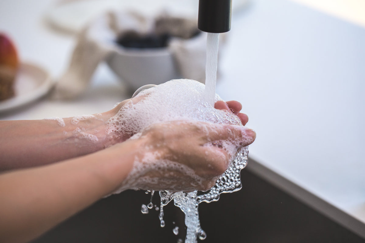 Person washing their hands with soap creating soap/suds bubbles